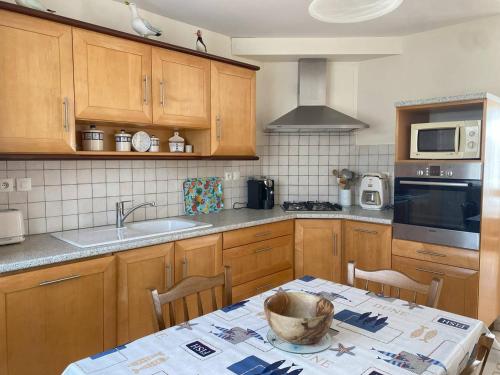 - une cuisine avec des placards en bois et une table avec un bol dans l'établissement Maison charmante à 300m de la mer, Ile Grande, parking inclus - FR-1-368-458, à Pleumeur-Bodou