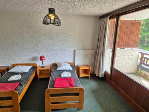 une chambre avec deux lits et une fenêtre dans l'établissement Appartement 2 pièces, balcon sud, pieds de pistes, animaux admis - FR-1-811-40, à Les Deux Alpes