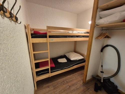 une chambre avec trois lits superposés dans une pièce dans l'établissement Studio fonctionnel au pied des pistes, centre station, animaux admis - FR-1-811-42, à Les Deux Alpes