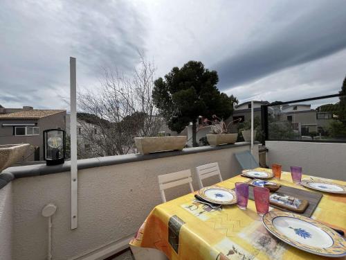 une table avec un chiffon de table jaune sur un balcon dans l'établissement Appartement avec Mezzanine, Climatisation et Parking, proche Plage, pour 4 personnes à Gruissan - FR-1-229-897, à Gruissan