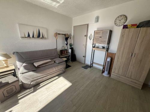 un salon avec un canapé et une horloge au mur dans l'établissement T2 proche plage avec parking privatif, 4 personnes - FR-1-701-90, à Valras-Plage