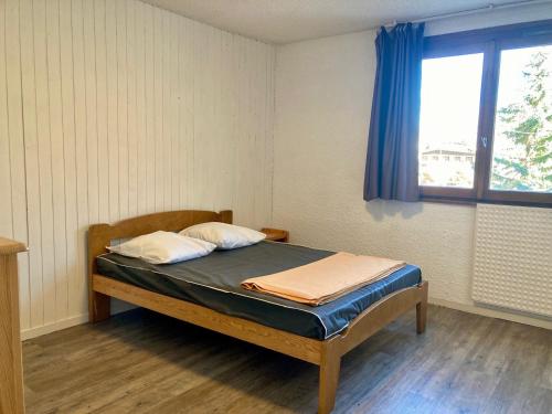 - une chambre avec un lit doté d'un rideau bleu et d'une fenêtre dans l'établissement Appartement fonctionnel 2 pièces, animaux admis, au pied des pistes - FR-1-811-41, à Les Deux Alpes