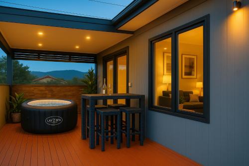 a patio with a hot tub and stools on a deck at Luxurious Hobart Holiday Home with Stunning Bay Views - Affordable, Family-Friendly, and Stylish in Sorell