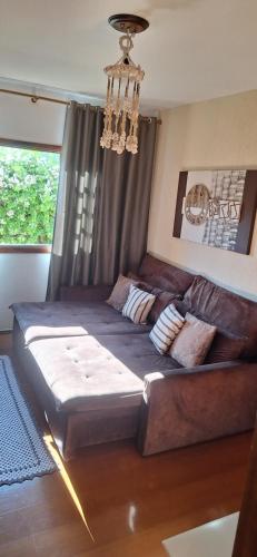 een grote bank in een woonkamer met een kroonluchter bij apartamento águas de lindoia itaigara in Águas de Lindóia