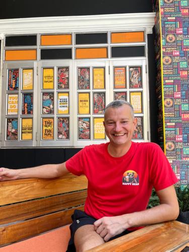a man in a red shirt sitting on a bench at Happy Bear Hostel Phu Quoc in Phu Quoc