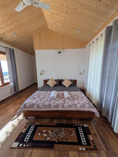 a bedroom with a large bed with a wooden ceiling at Sunshine Cottages in Bīr