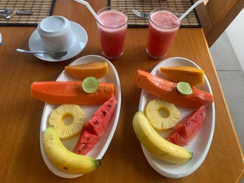 a plate of fruit on a table with two glasses of juice at Madiha Venus in Matara