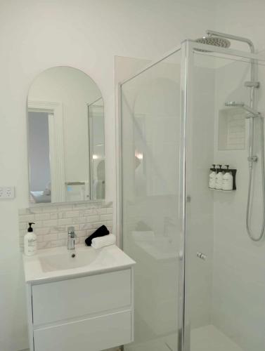 a white bathroom with a shower and a sink at Honeysuckle Inn - Violet Town in Violet Town
