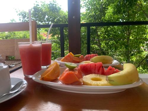 a plate of fruit on a table with a drink at Madiha Venus in Matara