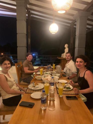 a group of people sitting around a wooden table at Madiha Venus in Matara