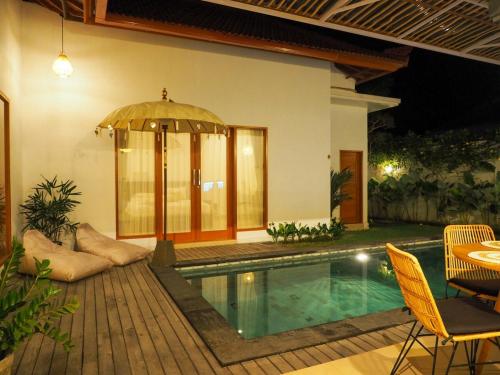 a house with a swimming pool with a table and an umbrella at MoHana Villa - A Minimal Canggu Oasis in Canggu
