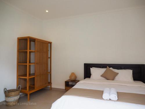 a bedroom with a bed and a book shelf at MoHana Villa - A Minimal Canggu Oasis in Canggu