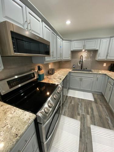 a kitchen with white cabinets and a stove top oven at HubCityJewel in Compton