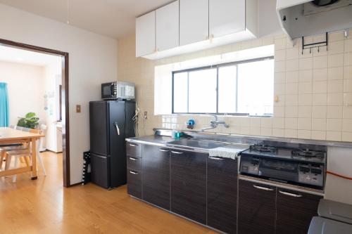 a kitchen with a black refrigerator and a sink at ocean blue mint海まで３分! 南房総最南端の１棟まるごと貸別荘 in Hongō