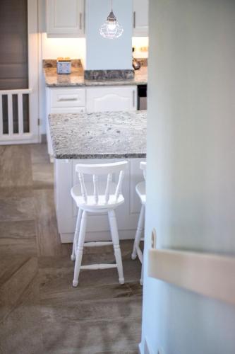 a kitchen with a white counter and white stools at Oceanview 3BR Villa with 3 Shared Pools and Beachfront Resort Access in Ocotal