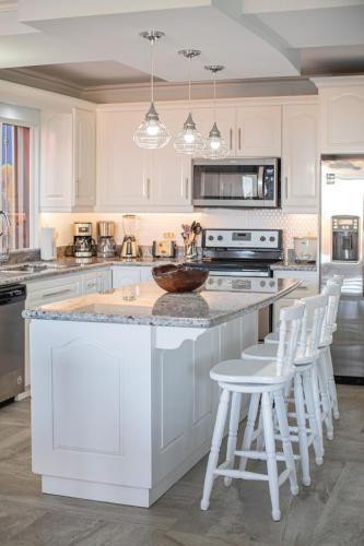 a kitchen with white cabinets and a island with bar stools at Oceanview 3BR Villa with 3 Shared Pools and Beachfront Resort Access in Ocotal