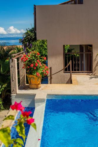 a swimming pool with flowers and a house at Oceanview 3BR Villa with 3 Shared Pools and Beachfront Resort Access in Ocotal