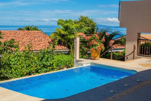 a blue swimming pool in front of a house at Oceanview 3BR Villa with 3 Shared Pools and Beachfront Resort Access in Ocotal