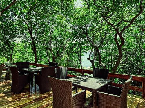 a wooden deck with tables and chairs and trees at ZHANG RESORT and DIVE CENTER in Daanbantayan