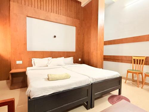 a bedroom with a bed with white sheets and a chair at NE Residency in Guwahati