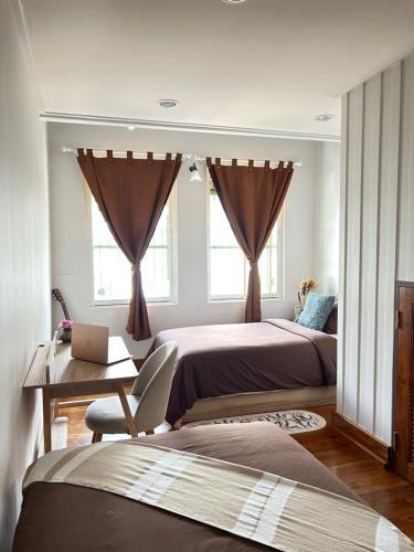 Un dormitorio con dos camas y un escritorio y dos ventanas. en Mookda House Chinatown BKK near MRT Samyot, en Khlong San