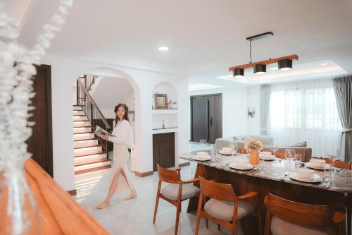 a woman walking in a living room with a table at Villa Abigail Chiang Mai in Chiang Mai