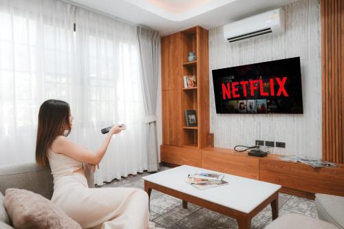 a woman in a living room playing a video game at Villa Abigail Chiang Mai in Chiang Mai