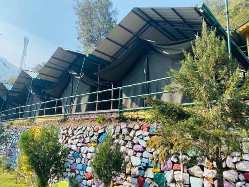 a building with a rock retaining wall and trees at Cradle of Life in Shivpuri