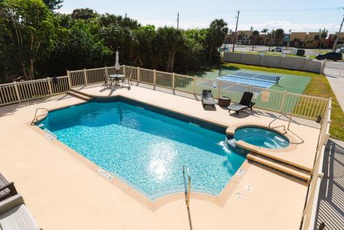a swimming pool with two chairs and a tennis court at Golden Sands Pearl - Florida's Top - ALL Private Beachfront with NEW Pickleball Court, Pool, Spa in Indialantic