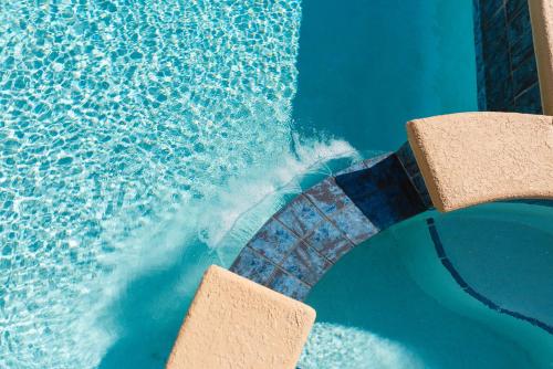 a water slide in a swimming pool with two chairs at Golden Sands Pearl - Florida's Top - ALL Private Beachfront with NEW Pickleball Court, Pool, Spa in Indialantic