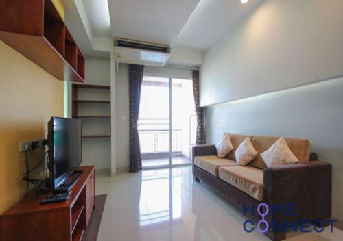 ein Wohnzimmer mit Sofa und Fernseher in der Unterkunft Lasalle Park Serviced Apartment at Lasalle 75 in Bangna