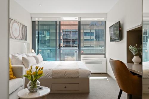 a bedroom with a bed and a couch and a desk at City Stays in Melbourne