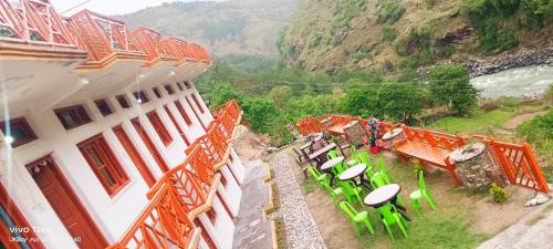a balcony of a building with green tables and chairs at Hotel Prakriti Darshan in Bhatwāri