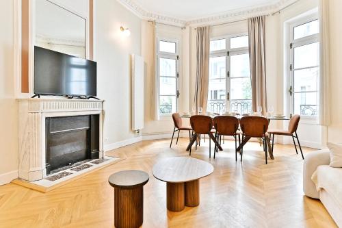 un salon avec une table et des chaises et une cheminée dans l'établissement Appartement moderne et climatisé - Arc de Triomphe, à Paris