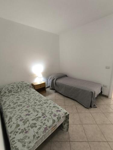 a bedroom with two beds and a table with a lamp at casa vacanza emanuele in Alezio