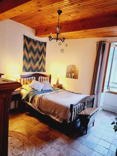 une chambre avec un lit et un plafond en bois dans l'établissement Maison et jardin coeur de village, à Sumène
