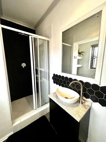 a bathroom with a sink and a shower with a mirror at Naby-My Stellenbosch Cottage in Stellenbosch