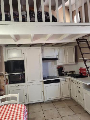 une cuisine avec des placards blancs et un lit en mezzanine dans l'établissement Le Barcares 100 m plage et commerces, à La Celle-sous-Gouzon