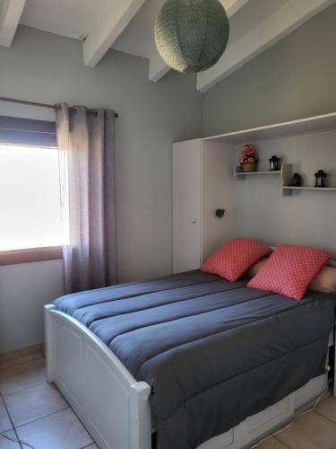 une chambre avec un lit avec des draps bleus et des oreillers rouges dans l'établissement Le Barcares 100 m plage et commerces, à La Celle-sous-Gouzon