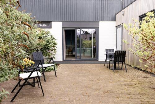 a patio with chairs and tables in front of a building at VlieMare Appartementen De Kluut in Oost-Vlieland