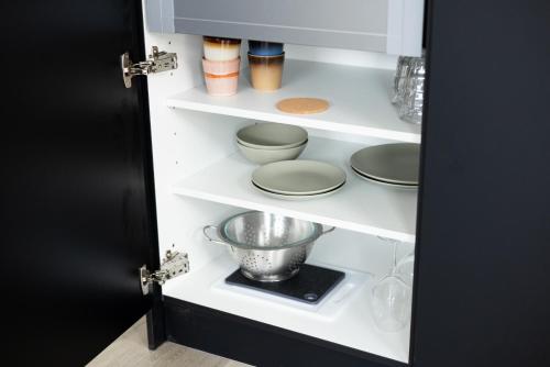 a kitchen pantry with plates and bowls on shelves at VlieMare Appartementen De Kluut in Oost-Vlieland