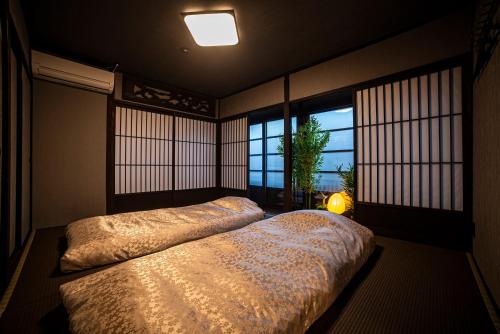 two beds in a room with windows and a lamp at おやど紀伊国屋籠町 in Nagasaki