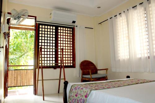 a bedroom with a bed and a fan and a window at Sandybridge Eco Farm at Relly's Restaurant in Puerto Princesa City
