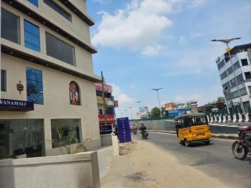 a yellow vehicle driving down a street next to a building at Hotel Vanamali in Tirupati
