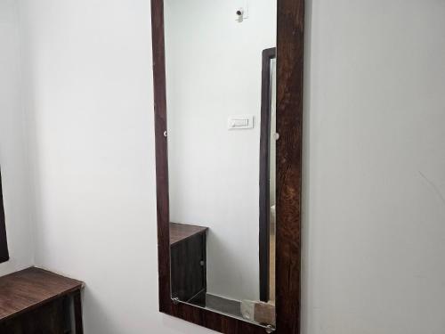 a mirror with a wooden frame on a wall at Hotel Vanamali in Tirupati