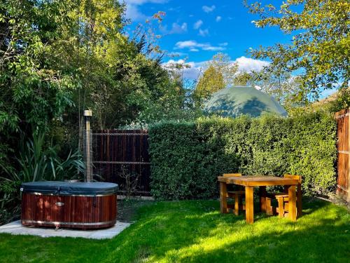 a garden with a wooden table and a tub at Hanmer Glamping in Hanmer Springs