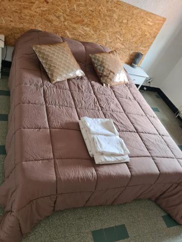 - un lit avec une couette brune et des oreillers dans l'établissement PLEIN CENTRE VILLE, parking gratuit, à Gap