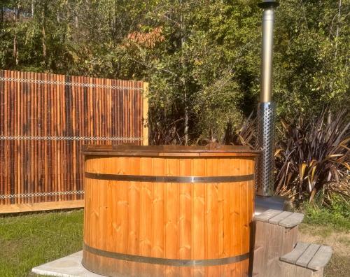 a wooden hot tub in a yard next to a fence at Hanmer Glamping in Hanmer Springs