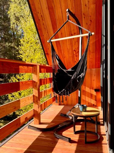 a hammock on a wooden porch with a table at Clonowo 2 in Borsk