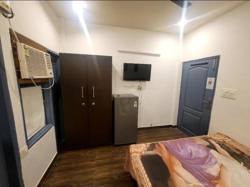a room with a bed and a tv and a door at Old School Appartment in Kapūrthala